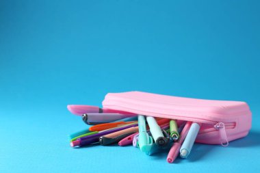 Açık mavi arka planda kalemler ve kalemler, yakın plan. Metin için boşluk