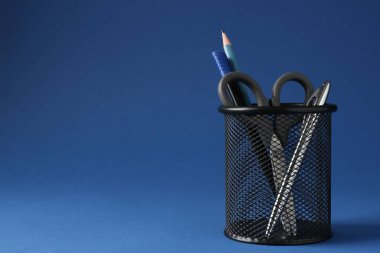 Koyu mavi arka planda kalem tutacağında farklı bir kırtasiye malzemesi. Metin için boşluk