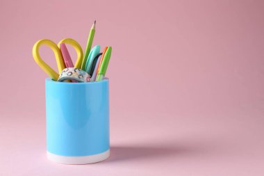 Pembe arka planda kalem tutacağında farklı bir kırtasiye malzemesi. Metin için boşluk