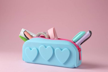 Pembe arka planda kalem kutusunda farklı kırtasiye malzemesi