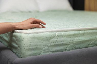 Yatakta yumuşak yatağa dokunan kadın, yakın plan.