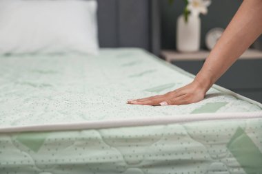 Yatakta yumuşak yatağa dokunan bir kadın, yakın plan. Metin için boşluk