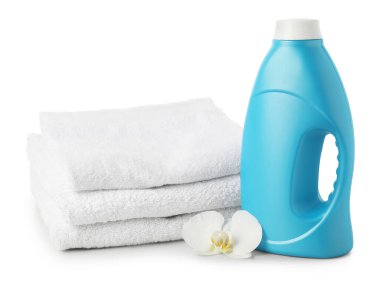 Bir şişe yumuşatıcı, istiflenmiş havlular ve beyaz üzerine izole edilmiş çiçek.