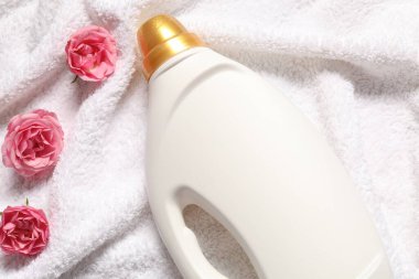 Bir şişe yumuşatıcı ve havlunun üstünde çiçekler.