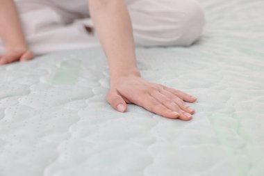 Yatakta yumuşak yatağa dokunan kadın, yakın plan.