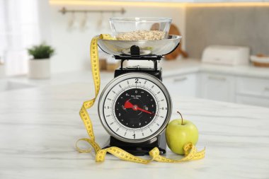 Yulaf ezmeli mutfak pulları, bant ve elmayı açık mermer masada iç mekanda ölçmek.