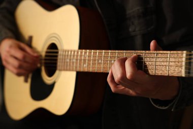 Siyah arkaplanda gitar çalan adam, yakın plan