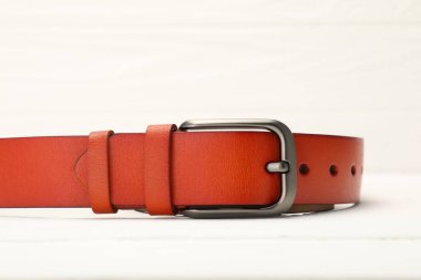 Beyaz masada bir turuncu deri kemer, yakın plan.