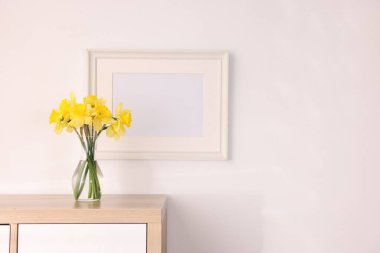 Vazodaki güzel nergisler ve evdeki dolabın üzerindeki resim çerçevesi, metin için yer