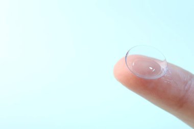 Açık mavi arka planda kontak lensli kadın, yakın plan. Metin için boşluk