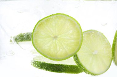 Soda tazeleniyor. Beyaz arka planda limon dilimleri var. Yakın plan.