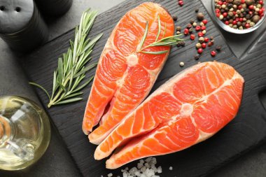 Deniz ürünleri. Çiğ somon bifteği, biberiye ve baharatlar gri masada.