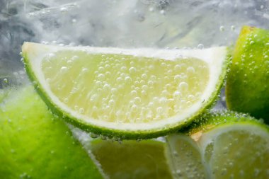 Koyu arkaplanda limon dilimleri ve buzla soda tazeleniyor. Yakın plan.