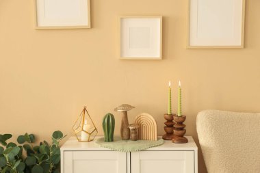 Havalı şamdanlar, yanan mumlar ve kapalı alandaki bej duvarın yanındaki dolaptaki diğer dekorlar.