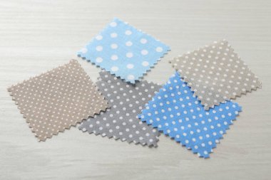 Beyaz ahşap masadaki farklı kumaşlardan örnekler, yakın plan.