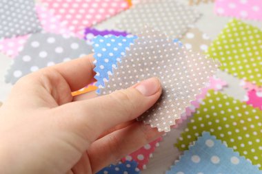 Beyaz ahşap masada farklı kumaşlardan örnekler taşıyan kadın, yakın plan.