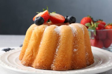 Açık gri masada pudra şekeri ve böğürtlenli Lezzetli kek, yakın plan.