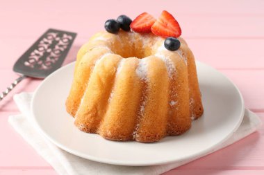 Pudra şekerli, dutlu ve pembe ahşap masadaki sunuculu lezzetli kek, yakın plan.