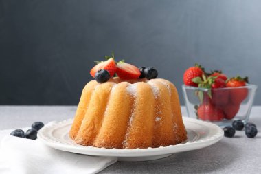 Açık gri masada pudra şekeri ve böğürtlenli Lezzetli kek, yakın plan.