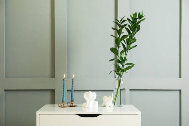 Işık duvarının yanındaki çekmecelerin üzerinde yanan mumlar olan şamdanlar.