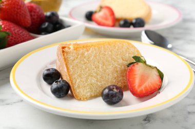 Beyaz mermer masanın üzerinde meyveli kek parçaları, yakın plan.