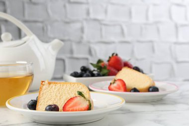 Lezzetli kek parçaları, böğürtlenli ve beyaz mermer masada çay, yakın plan.