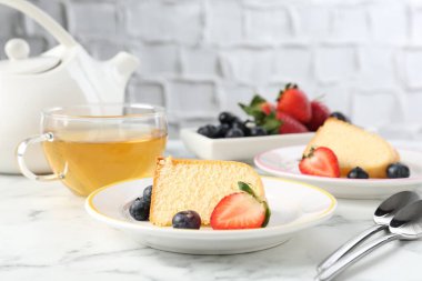 Lezzetli kek parçaları, böğürtlenli ve beyaz mermer masada çay, yakın plan.