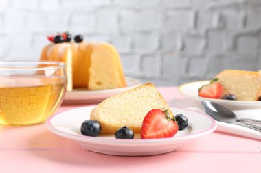 Böğürtlenli kek ve pembe ahşap masada çay, yakın plan.