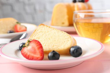 Böğürtlenli kek ve pembe ahşap masada çay, yakın plan.