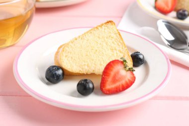 Böğürtlenli kek ve pembe ahşap masada çay, yakın plan.