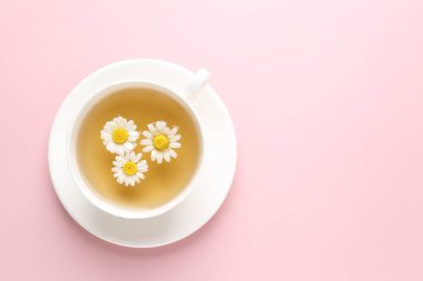 Fincanda nefis papatya çayı ve pembe arka planda taze çiçekler. Metin için boşluk