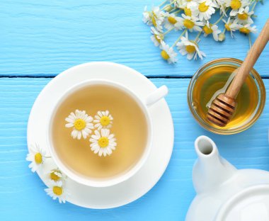 Lezzetli papatya çayı, taze çiçekler, limon ve bal açık mavi ahşap masa, düz uzanmış