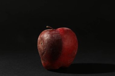 Siyah arka planda bir çürük kırmızı elma