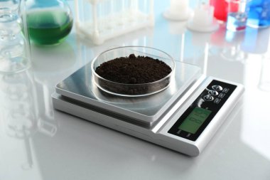 Beyaz ayna masasındaki Petri kabı ve diğer laboratuvar camlarıyla ölçeklendir, yakın plan.