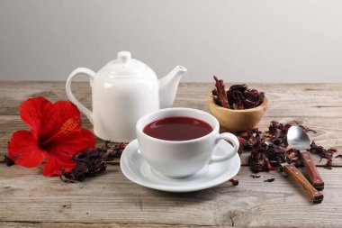 Lezzetli amber çayı fincanda, çaydanlıkta, kuru roselle sepals ve ahşap masada çiçek