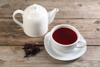 Lezzetli amber çayı fincanda, çaydanlık ve kuru roselle sepals ahşap masada