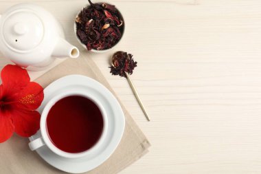 Fincanda leziz amber çayı, çaydanlık, kuru roselle sepals ve açık ahşap masa üzerinde çiçek, düz yatak. Metin için boşluk
