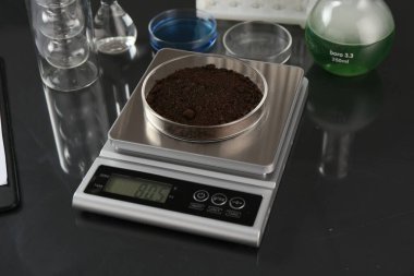 Siyah ayna masasındaki Petri kabı ve diğer laboratuvar camlarıyla ölçeklendir, yakın plan.