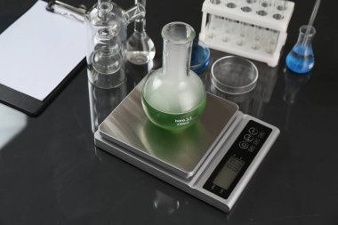 Siyah ayna masasının üzerinde numune ve diğer laboratuvar camlarıyla ölçeklendir.