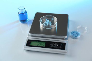 Petri kabı ve diğer cam parçalarıyla beyaz masa üzerindeki renk ışıklarıyla ölçeklendir, yakın plan