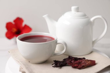 Fincanda leziz amber çayı, çaydanlık ve kuru roselle sepals beyaz masada, yakın plan.