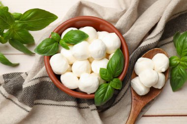 Lezzetli mozzarella peynir topları kasede, fesleğen ve kaşık açık ahşap masada, düz yatıyordu.