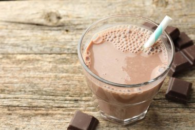 Bardakta çikolatalı süt ve ahşap masada parçalar, yakın plan. Metin için boşluk