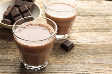 Bardakta çikolatalı süt ve ahşap masada parçalar, yakın plan. Metin için boşluk