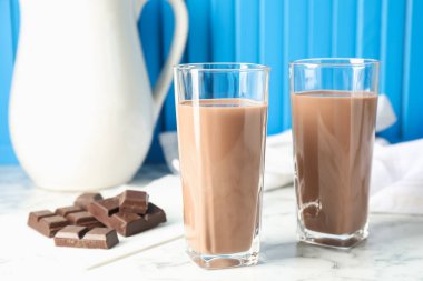 Bardakta çikolatalı süt ve beyaz mermer masada malzeme, yakın plan.