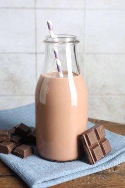 Cam şişede çikolatalı süt ve ahşap masada malzeme.