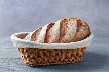 Gri ahşap masada sepette bir somun ekmek