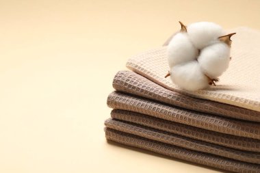 Temiz waffle havluları ve bej arka planda pamuk çiçeği, yakın plan. Metin için boşluk