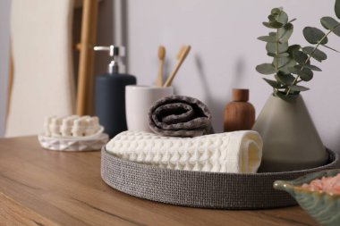 Temiz waffle havluları ve diğer banyo ürünleri ahşap şifoniyerde, yakın plan.