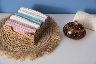 Hasır sepetin içinde temiz waffle havluları banyoda beyaz şifoniyerin üzerinde, yakın plan.